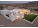 Aerial view of a modern desert home with a backyard, string lights, and desert scenery at dusk at 15574 N Brielles Way, Maricopa, AZ 85139