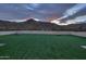 Evening view of the backyard's artificial turf with scenic mountain backdrop, enhancing outdoor enjoyment at 15574 N Brielles Way, Maricopa, AZ 85139