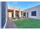 Backyard featuring artificial grass, desert landscaping, a fire pit, modern architecture, and string lighting at 15574 N Brielles Way, Maricopa, AZ 85139