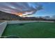 Twilight scene of backyard featuring artificial turf, cornhole, and distant mountains, creating a serene setting at 15574 N Brielles Way, Maricopa, AZ 85139