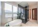 Luxurious bathroom featuring a freestanding tub, glass-enclosed shower, and mountain views from large picture window at 15574 N Brielles Way, Maricopa, AZ 85139