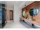 Modern bathroom with dual stone vessel sinks, wood accent wall, walk-in shower, and sleek design, with marble floor at 15574 N Brielles Way, Maricopa, AZ 85139