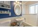 Charming bathroom featuring blue walls, beadboard paneling, and a stylish oval mirror over the pedestal sink at 1721 W Weldon Ave, Phoenix, AZ 85015