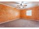 Spacious bedroom with unique orange textured walls, ceiling fan, and neutral carpet at 1721 W Weldon Ave, Phoenix, AZ 85015