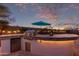 Outdoor kitchen featuring a built-in grill, bar seating, and a vibrant sunset backdrop, creating the perfect space for entertaining at 17751 W Desert View Ln, Goodyear, AZ 85338