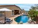 Stunning backyard pool with rock accents, outdoor kitchen with bar seating, and lush landscaping, providing a private oasis at 17751 W Desert View Ln, Goodyear, AZ 85338