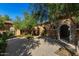 Beautiful courtyard with stone archways, lush trees providing shade, and inviting design at 18938 W Luke Ave, Litchfield Park, AZ 85340