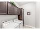 Laundry room with white washer and dryer, dark wood cabinets and tiled floor at 18938 W Luke Ave, Litchfield Park, AZ 85340