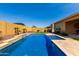 A backyard oasis showcasing a refreshing pool with travertine decking and desert landscaping at 18938 W Luke Ave, Litchfield Park, AZ 85340