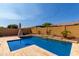 Inviting backyard pool area with a privacy wall, desert landscaping, and umbrella for shade at 18938 W Luke Ave, Litchfield Park, AZ 85340