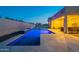 A well-lit pool featuring a modern design with a waterfall and an outdoor basketball hoop at 21397 S 215Th Way, Queen Creek, AZ 85142