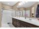 Bright bathroom featuring double sinks, a dark vanity, a shower, a large mirror and nice decor at 21609 N Diamond Dr, Maricopa, AZ 85138