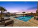 Stunning waterfront pool and spa area with a fire pit, set against a picturesque sunset backdrop with palm trees at 21609 N Diamond Dr, Maricopa, AZ 85138