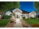 Charming home with stone accents, lush landscaping, and a welcoming walkway, enhanced by elegant outdoor lighting at 23420 S 202Nd St, Queen Creek, AZ 85142