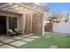 Backyard featuring artificial turf, concrete pavers, covered patio with curtains, and desert landscaping at 3518 S Posse Trl, Gilbert, AZ 85297