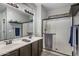 Well-lit bathroom with dual sinks, sleek vanity, and frameless glass shower door at 3518 S Posse Trl, Gilbert, AZ 85297