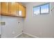 Bright laundry room with tile floors, window, and overhead wood cabinets at 3614 W Alyssa Ln, Phoenix, AZ 85083