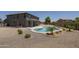 Wide view of a backyard featuring desert landscaping, a kidney-shaped pool, and a covered patio for relaxed outdoor living at 6993 S Sharon Ct, Chandler, AZ 85249