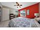 Comfortable bedroom with a red accent wall, ceiling fan, and natural light at 7132 W Vermont Ave, Glendale, AZ 85303