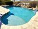 Refreshing pool with a baja shelf and rock waterfall, surrounded by lush landscaping and travertine pavers at 8386 E Arroyo Seco Rd, Scottsdale, AZ 85266