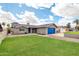 A well-maintained single-story home showcasing its manicured front lawn and blue garage door at 8637 E Jackrabbit Rd, Scottsdale, AZ 85250