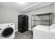 Laundry area with gray tile flooring, black refrigerator, washer, dryer, and metal shelving at 8637 E Jackrabbit Rd, Scottsdale, AZ 85250