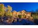 Warm lighting showcases a desert-landscaped home with neutral tones and well-manicured shrubs at twilight at 9431 N Summer Hill Blvd, Fountain Hills, AZ 85268