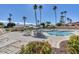 Community pool area with lounge chairs, tables with umbrellas, well-maintained landscaping, and blue skies at 9803 N 100Th Pl, Scottsdale, AZ 85258