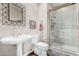 Cozy bathroom features a walk-in shower with glass doors, pedestal sink, and decorative mirror at 11664 E Del Timbre Dr, Scottsdale, AZ 85259