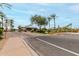 Community entrance with covered gate, palm trees, desert landscaping, and well-maintained street at 11664 E Del Timbre Dr, Scottsdale, AZ 85259