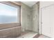 Modern walk-in shower with gray tiling, a rainfall showerhead, and a frameless glass enclosure at 12462 N 75Th Ln, Peoria, AZ 85381