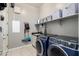 Well-lit laundry room featuring modern washer and dryer, storage shelves, and tile flooring at 14845 W Georgia Dr, Surprise, AZ 85379