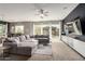 Bright living room with a gray sectional, backyard view, and a modern entertainment center at 14845 W Georgia Dr, Surprise, AZ 85379
