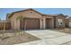 A view of the home's front exterior showcasing the driveway, garage, desert landscaping, and covered front porch at 15053 W Gray Fox Trl, Surprise, AZ 85387