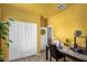 Bright and airy room featuring white closet doors, yellow walls, and a unique sewing setup at 16510 W Tether Trl, Surprise, AZ 85387