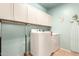 This laundry room offers a front-load washer, a dryer, upper cabinets, and a hanging rack at 16510 W Tether Trl, Surprise, AZ 85387