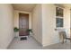 Inviting covered porch with a brown front door, neutral wall and accent plants at 21867 N 263Rd Dr, Buckeye, AZ 85396