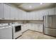 Convenient laundry room with abundant white cabinets, granite countertops, stainless steel appliances, and travertine flooring at 22500 N 97Th St, Scottsdale, AZ 85255