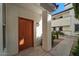 Covered entryway with orange door, sidelight window, and desert landscaping at 2992 N Miller Rd # 103, Scottsdale, AZ 85251
