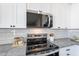 Kitchen featuring white cabinets, gray countertops, stainless steel microwave and oven with a subway tile backsplash at 3624 W Whitten St, Chandler, AZ 85226