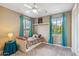 Bedroom with a white bed frame, ceiling fan, and two windows with blue curtains at 3713 E Cat Balue Dr, Phoenix, AZ 85050