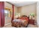 Cozy bedroom featuring a queen bed, neutral walls, side tables with lamps, and a window with red curtains at 3713 E Cat Balue Dr, Phoenix, AZ 85050