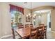 Dining room with a wooden table, chandelier, and a large window showing the exterior of the home at 3713 E Cat Balue Dr, Phoenix, AZ 85050