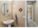 Powder room featuring a pedestal sink, round mirror, and decorative wall art at 3713 E Cat Balue Dr, Phoenix, AZ 85050