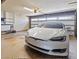 Spacious garage featuring a white Tesla car, built-in shelving, and an automatic door opener at 4001 E Cannon Dr, Phoenix, AZ 85028