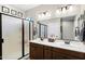 Well-lit bathroom with double sinks, wood cabinets, large mirror, and a glass door shower at 42186 W Cribbage Rd, Maricopa, AZ 85138