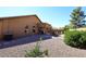 Backyard patio area with chairs, gravel, and outdoor kitchen area with home on sunny day at 45558 W Mountain View Rd, Maricopa, AZ 85139