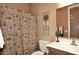 Traditional bathroom featuring a patterned shower curtain and a palm tree-themed decor at 45558 W Mountain View Rd, Maricopa, AZ 85139