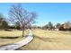 Sidewalk walking path winding through grassy area with trees, community homes on sunny day at 45558 W Mountain View Rd, Maricopa, AZ 85139