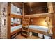 Cozy bunk room featuring wood paneled walls, sleeping for six, ladders for access and adjacent bathroom at 51238 N Pinal Ranch Rd, Miami, AZ 85539
